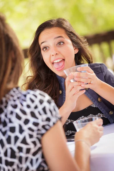 Uttrycksfull ung vuxen kvinna med drinkar och prata med hennes vän utomhus — Stockfoto