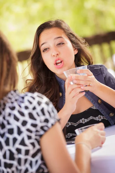 Ekspresyjny młoda kobieta dorosłych napić się drinka i rozmowa z jej przyjaciel na zewnątrz — Zdjęcie stockowe
