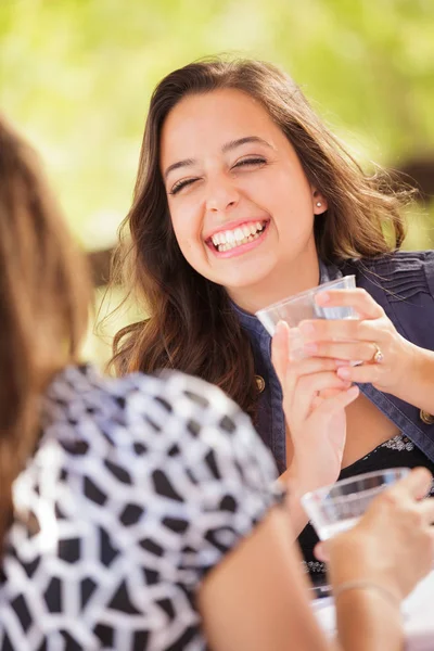 Expresiva mujer joven adulta tomando bebidas y hablando con su amiga al aire libre —  Fotos de Stock