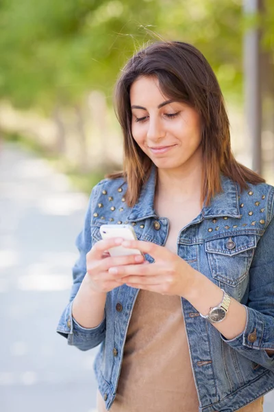 Piękna młoda kobieta etnicznych za pomocą jej zewnątrz Smartphone. — Zdjęcie stockowe