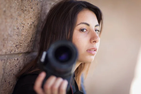 Junge erwachsene ethnische Fotografin gegen Wand mit Kamera — Stockfoto