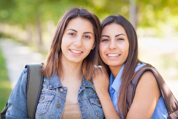 Two Beautiful Young Ethnic Twin Sisters With Backpacks Walking Outdoors. Royalty Free Stock Images