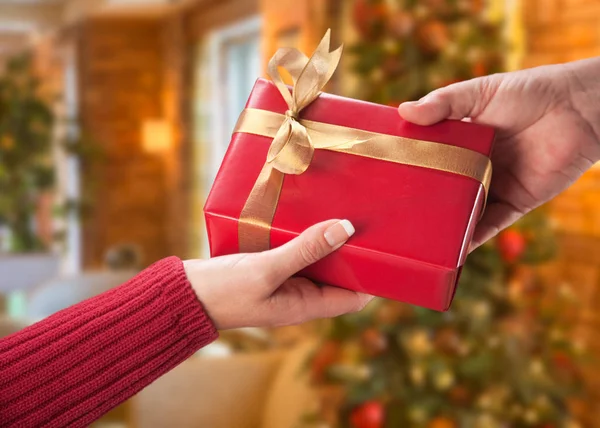 Άνδρας και γυναίκα ανταλλαγή δώρων, μπροστά από το στολισμένο χριστουγεννιάτικο δέντρο — Φωτογραφία Αρχείου
