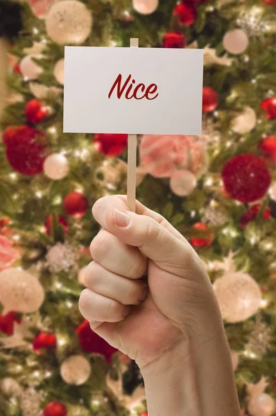 Hand hält schöne Karte vor geschmücktem Weihnachtsbaum. — Stockfoto