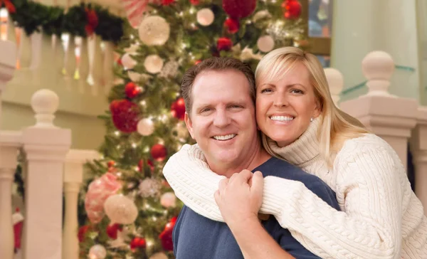 Καυκάσιος ζευγάρι αγκαλιάζει μπροστά από το στολισμένο χριστουγεννιάτικο δέντρο. — Φωτογραφία Αρχείου