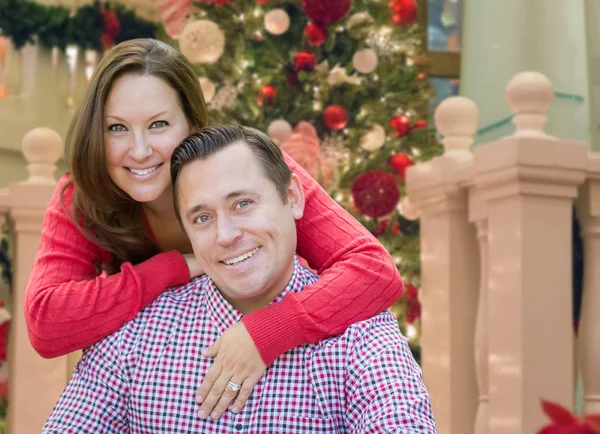 Casal caucasiano abraçando na frente da árvore de Natal decorada . — Fotografia de Stock