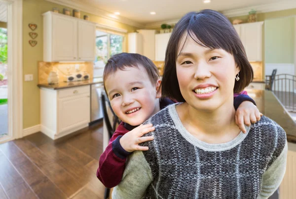 Madre china y niño de raza mixta dentro de hermosa cocina . — Foto de Stock