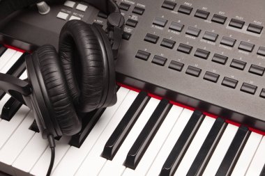 Listening Headphones Laying on Electronic Synthesizer Keyboard clipart