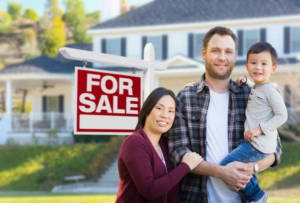 Blandad ras kinesiska och kaukasiska föräldrar och barn framför huset och för försäljning fastigheter tecken. — Stockfoto