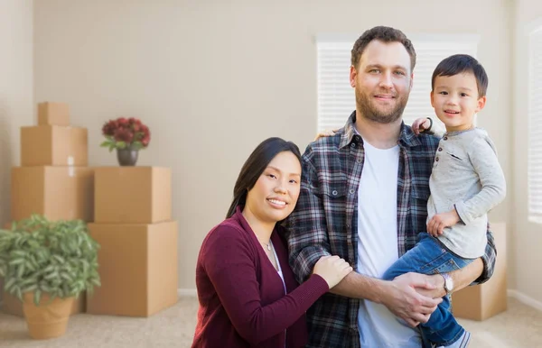 Blandad ras kinesiska och kaukasiska föräldrar och barn släpper tomt rum med flyttlådor. — Stockfoto