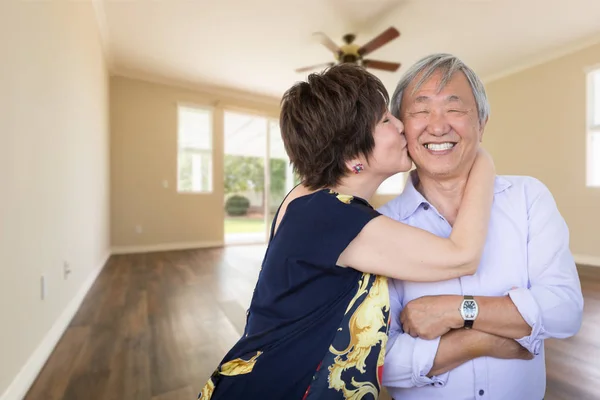 Feliz sénior chino pareja besos dentro vacío habitación de nuevo casa —  Fotos de Stock