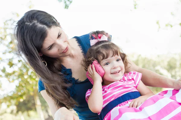 Mère de race mixte et fille de bébé mignon jouant avec le téléphone portable dans le parc . — Photo