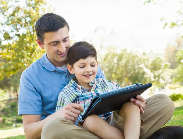 Padre e hijo felices jugando en una tableta de computadora afuera . — Foto de Stock