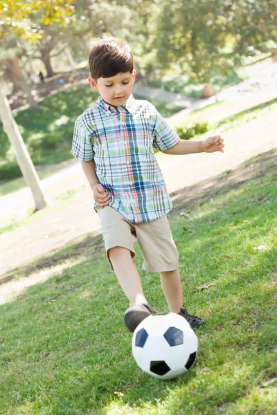 Ładny chłopiec gra z piłki nożnej na świeżym powietrzu w parku. — Zdjęcie stockowe
