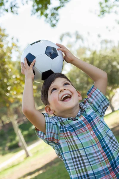 Netter kleiner Junge, der draußen im Park mit Fußball spielt. — Stockfoto