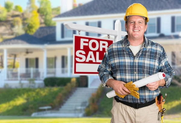 Dodavatel s plány a tvrdý klobouk před pro prodej nemovitostí znamení a domě. — Stock fotografie