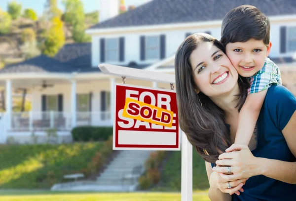 Joven madre e hijo en frente de Vendido para la venta Real Estate Sign and House . — Foto de Stock