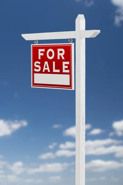 Links tegenover voor verkoop onroerend goed teken op een blauwe hemel met wolken. — Stockfoto