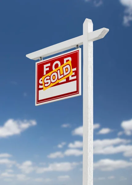 Links gegenüber verkauft Immobilienschild auf blauem Himmel mit Wolken. — Stockfoto