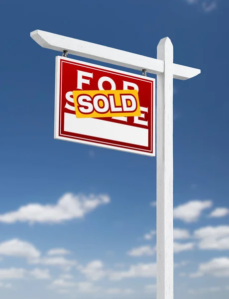 Links gegenüber verkauft Immobilienschild auf blauem Himmel mit Wolken. — Stockfoto