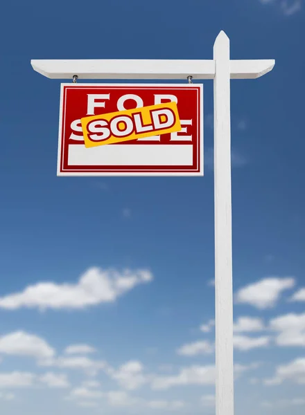 Links gegenüber verkauft Immobilienschild auf blauem Himmel mit Wolken. — Stockfoto