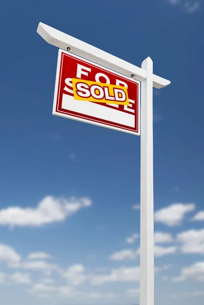 Links gegenüber verkauft Immobilienschild auf blauem Himmel mit Wolken. — Stockfoto