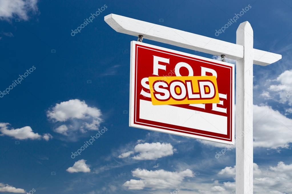 Left Facing Sold For Sale Real Estate Sign Over Blue Sky and Clouds With Room For Your Text.