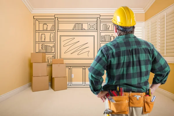 Contractor Standing Indoors with Moving Boxes Looking At Line Drwaing of Entertainment Unit on Wall. — Stock Photo, Image