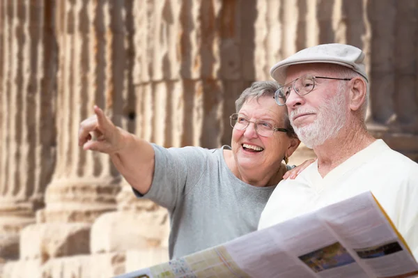 Buon anziano adulto coppia turisti con brochure accanto a rovine colonna antica . — Foto Stock