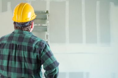 Contractor in Hard Hat Looking at Drywall. clipart