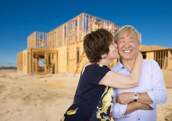 Pareja de adultos mayores chinos besándose frente a un nuevo marco de la casa en el sitio de construcción . —  Fotos de Stock