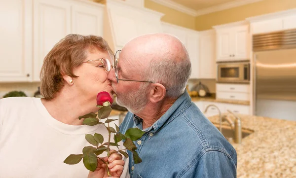 Glücklich Senior erwachsener Mann gibt rote Rose an seine Frau in der Küche — Stockfoto