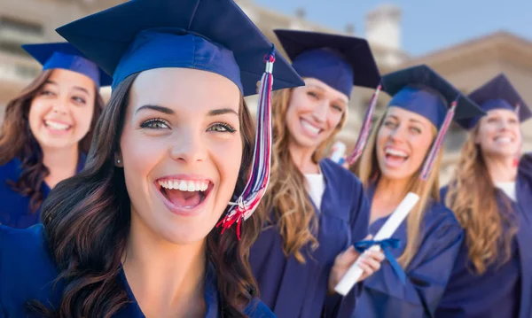 Glückliche Abschlussgruppe von Mädchen in Mütze und Kleid feiert auf dem Campus. — Stockfoto