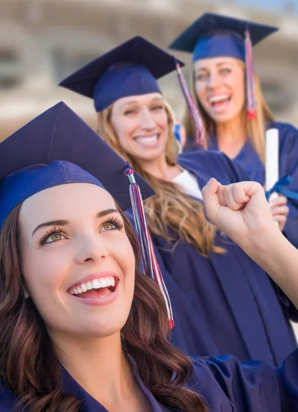 Glückliche Abschlussgruppe von Mädchen in Mütze und Kleid feiert auf dem Campus. — Stockfoto