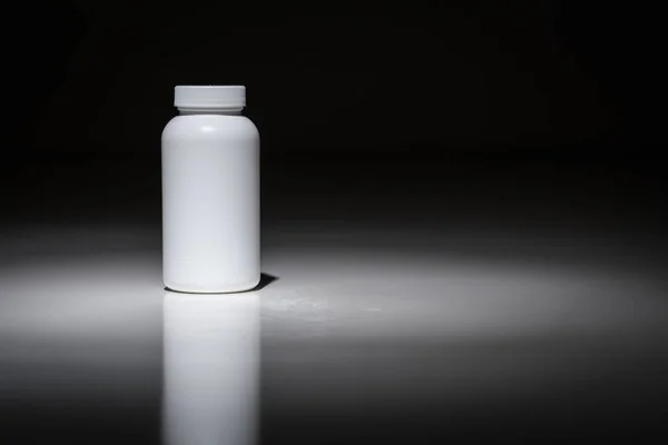 Κενό μπουκάλι λευκό έτοιμο για το κείμενό σας κάτω από το φως σημείων. — Φωτογραφία Αρχείου