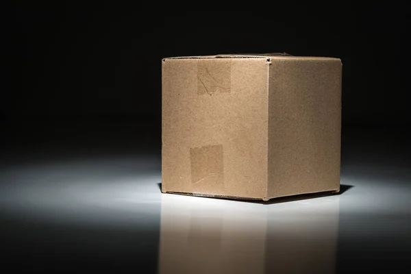 Caja de envío de cartón en blanco bajo punto de luz . — Foto de Stock