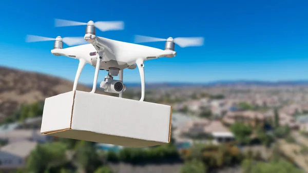 Drone Quadcopter du système d'aéronef sans pilote (UAS) transportant un paquet blanc au-dessus du voisinage . — Photo