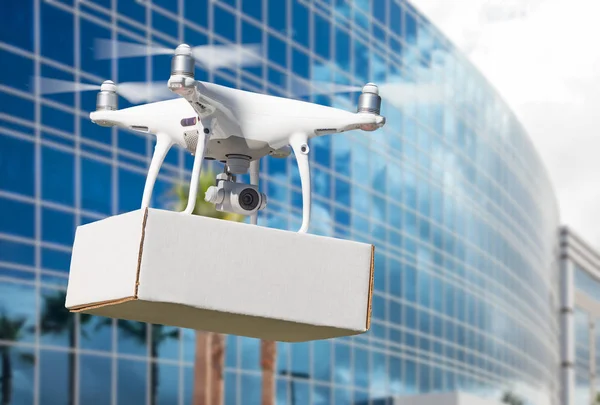 Sistema de aviones no tripulados (UAS) Quadcopter Drone que lleva el paquete en blanco cerca del edificio corporativo . —  Fotos de Stock