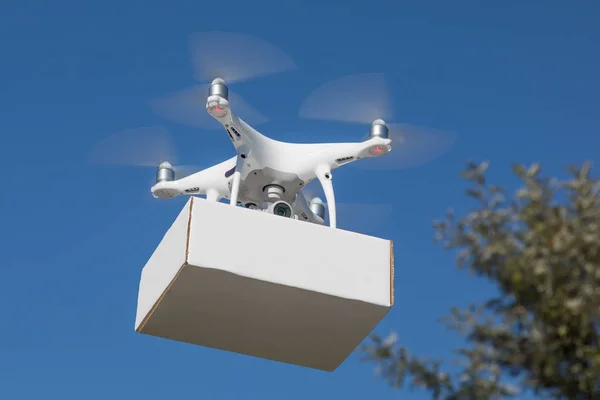 Sistema de aviones no tripulados (UAS) Quadcopter Drone que lleva el paquete en blanco en el aire . —  Fotos de Stock