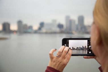 Woman Taking Pictures of The New Orleans Skyline with Her Smart Phone clipart