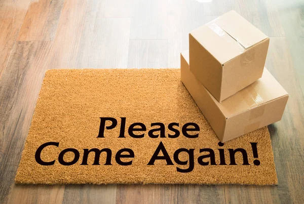 Por favor, venha novamente tapete de boas-vindas no chão de madeira com expedição de caixas — Fotografia de Stock