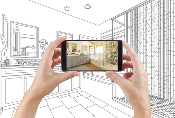 Manos sosteniendo el teléfono inteligente con la foto del baño principal en la pantalla y el dibujo detrás . — Foto de Stock