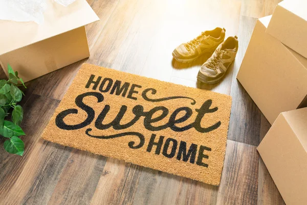 Otthon, édes otthon üdvözlő szőnyeg, mozgó dobozok, a cipők és a növény a kemény fa padló — Stock Fotó