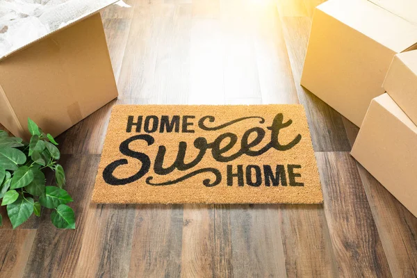 Otthon, édes otthon üdvözlő szőnyeg, mozgó dobozok, és a növény a kemény fa padló. — Stock Fotó
