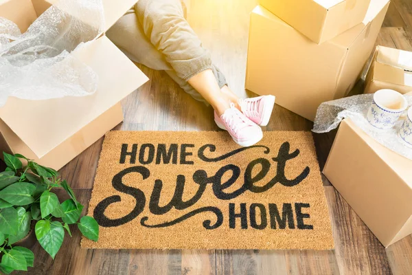 Woman Wearing Sweats Relaxing Near Home Sweet Home Welcome Mat, Moving Boxes and Plant. — Stock Photo, Image