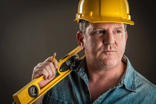 Serious Contractor in Hard Hat Holding Level and Pencil With Dramatic Lighting. — Stock Photo, Image