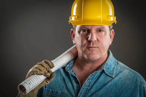 Serious Contractor in Hard Hat Holding Floor Plans With Dramatic Lighting. — Stock Photo, Image