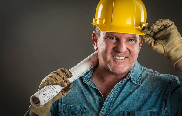 Smiling Contractor in Hard Hat Holding Floor Plans With Dramatic Lighting. — Stock Photo, Image