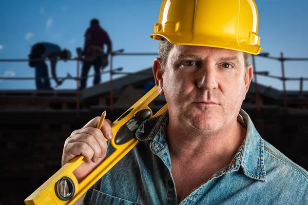 Contratante sério em Hard Hat Holding Nível e lápis no canteiro de obras . — Fotografia de Stock