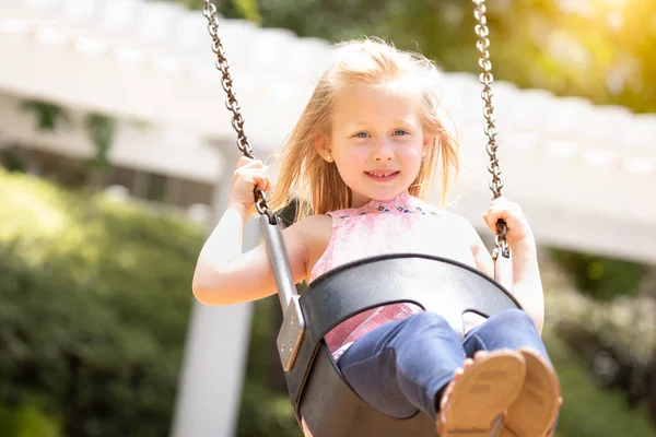 Menina muito jovem se divertindo nas oscilações no parque infantil — Fotografia de Stock